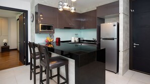 A modern kitchen with a central island, stainless steel appliances, and a dark-toned door. - Elegant 2BR Apartment RGN B411 in Laguna (Choeng Thale)