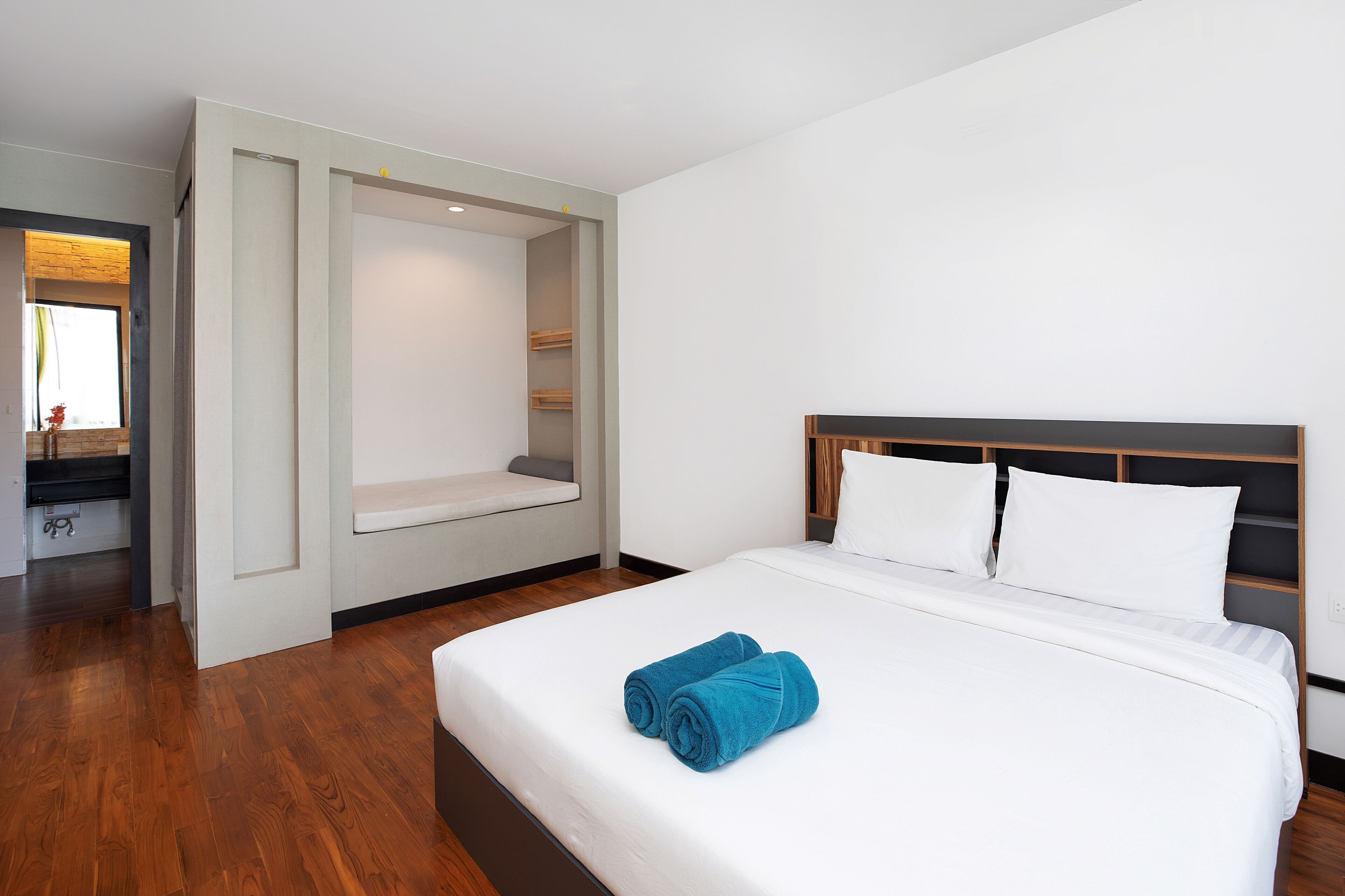 Ein modernes Hotelzimmer mit einem großen Bett, einer eingebauten Bank und einer kleinen Sitzecke.