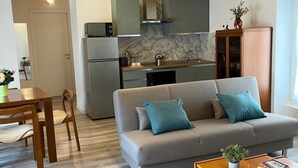 Una sala moderna con un sofá gris, una mesa de centro de madera y un comedor con mesa y sillas.