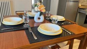 Una mesa de comedor dispuesta con platos, vasos y un florero.