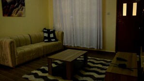 Un salon avec un canapé, une table basse, un tapis et une porte.