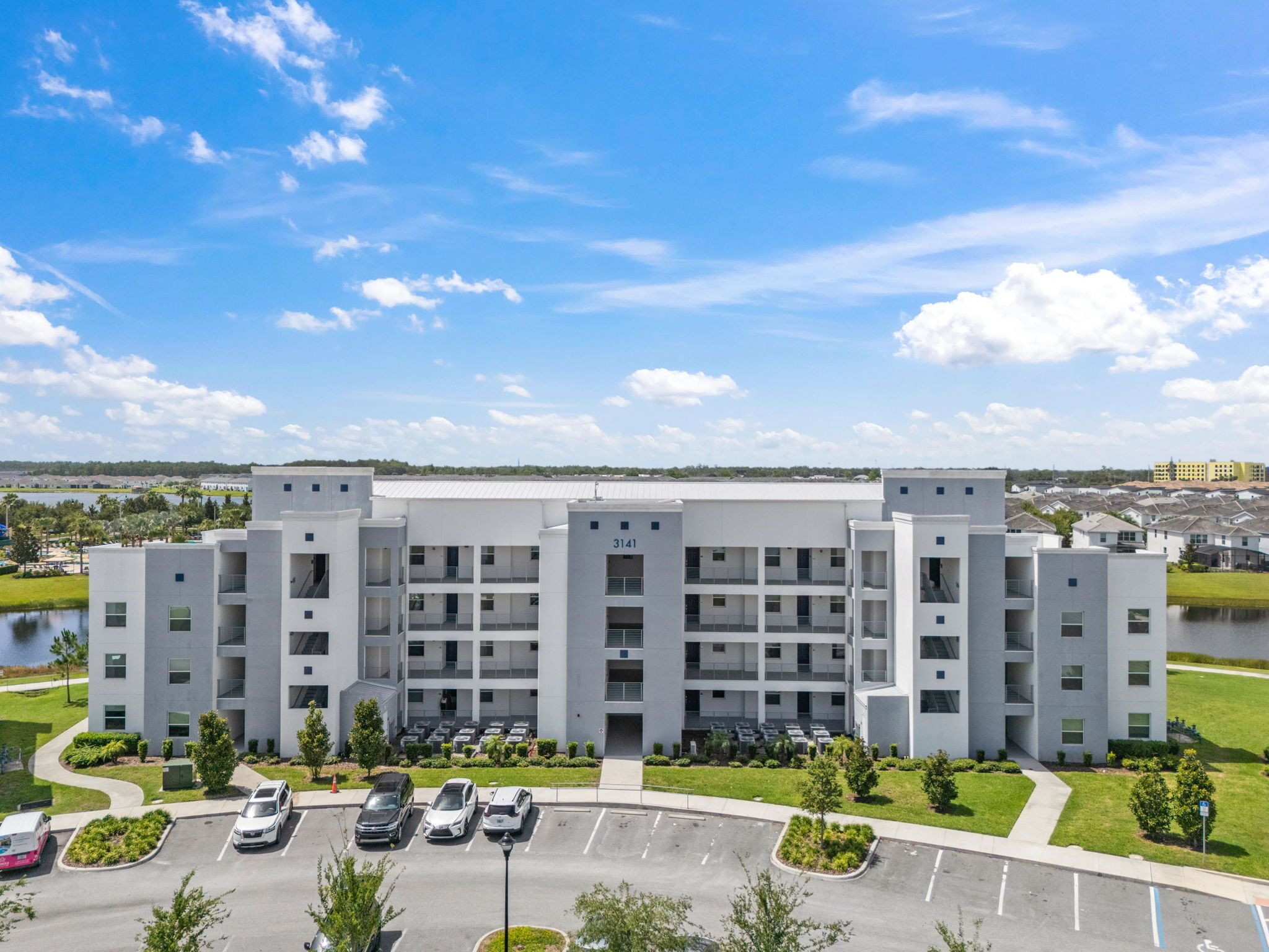 A multi-story building with a parking lot in front.