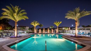 Piscina amb una profunditat de 0,9 metres, envoltada de palmeres i gandules, amb un cel nocturn clar al fons.