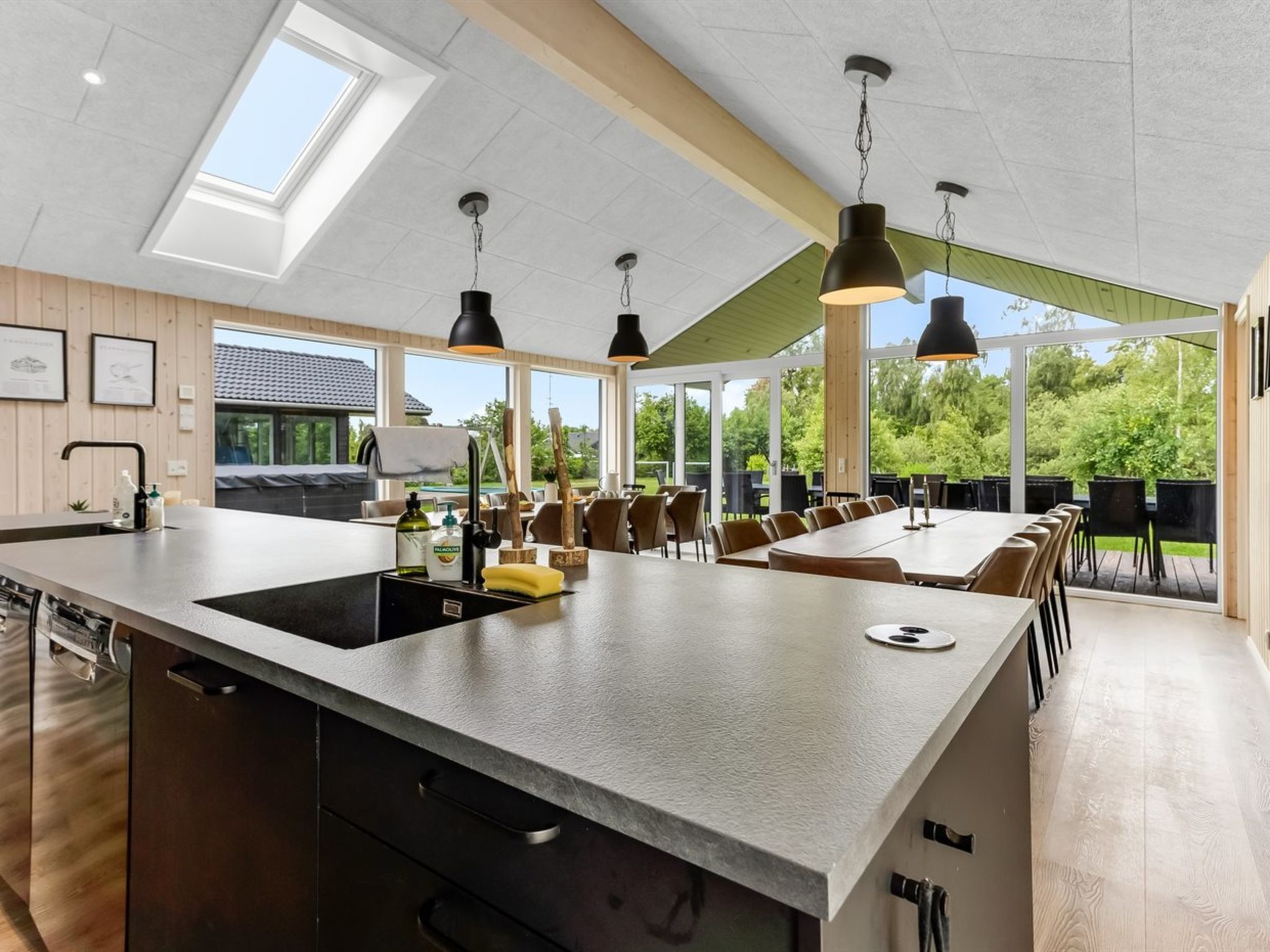 Eine moderne Küche mit einer großen Kochinsel, Pendelleuchten und Blick auf die Außenpatio-Terrasse.