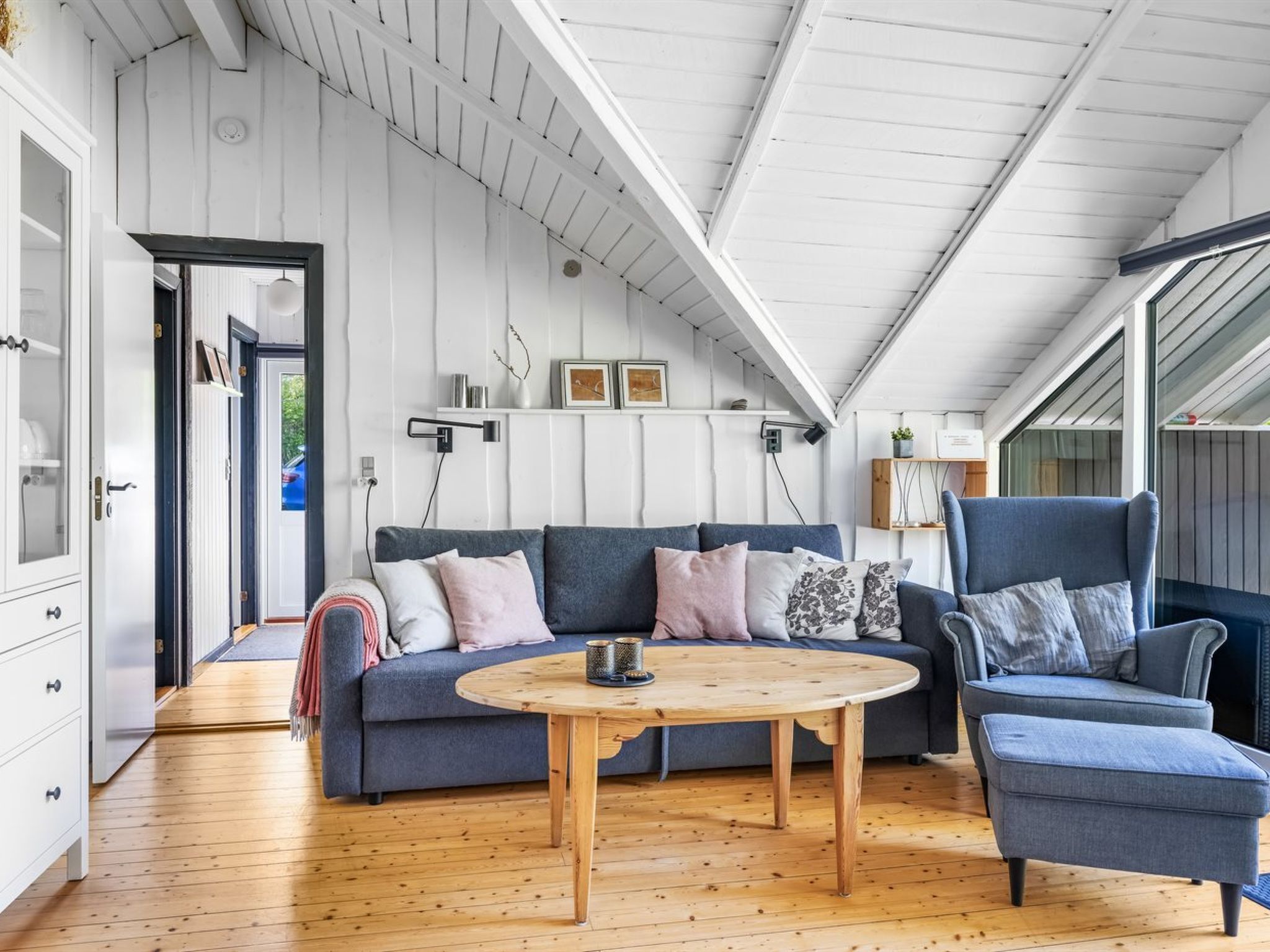 Un salon chaleureux avec un canapé bleu, une table basse ronde en bois et un fauteuil bleu.