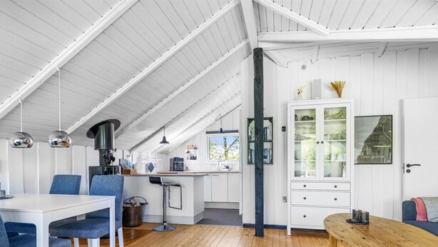 Una cocina estilo loft muy amplia con techos altos, piso de madera y una zona de comedor con sillas tapizadas en azul.