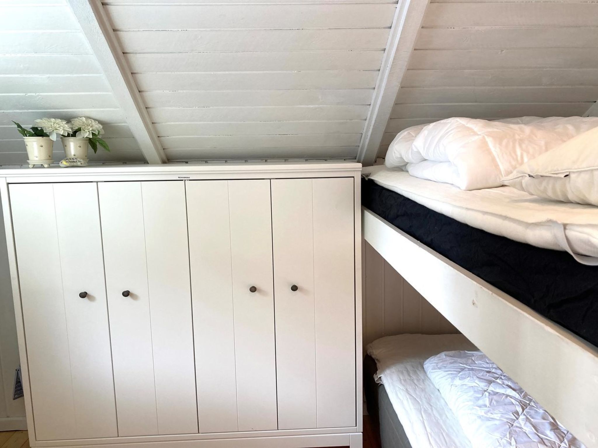 Een kamer in een studentencomplex met een stapelbed en een witte garderobe.