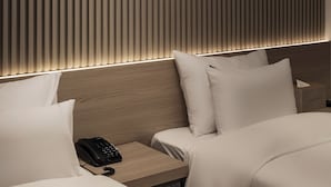 A modern hotel room with a slatted wall design, a bedside telephone, and a neatly made bed. - 21heritage hotel (Wonju)