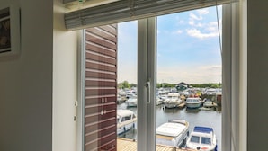 A view from a room with a large window overlooking a marina with several boats docked. - Kingsmere (Norwich)