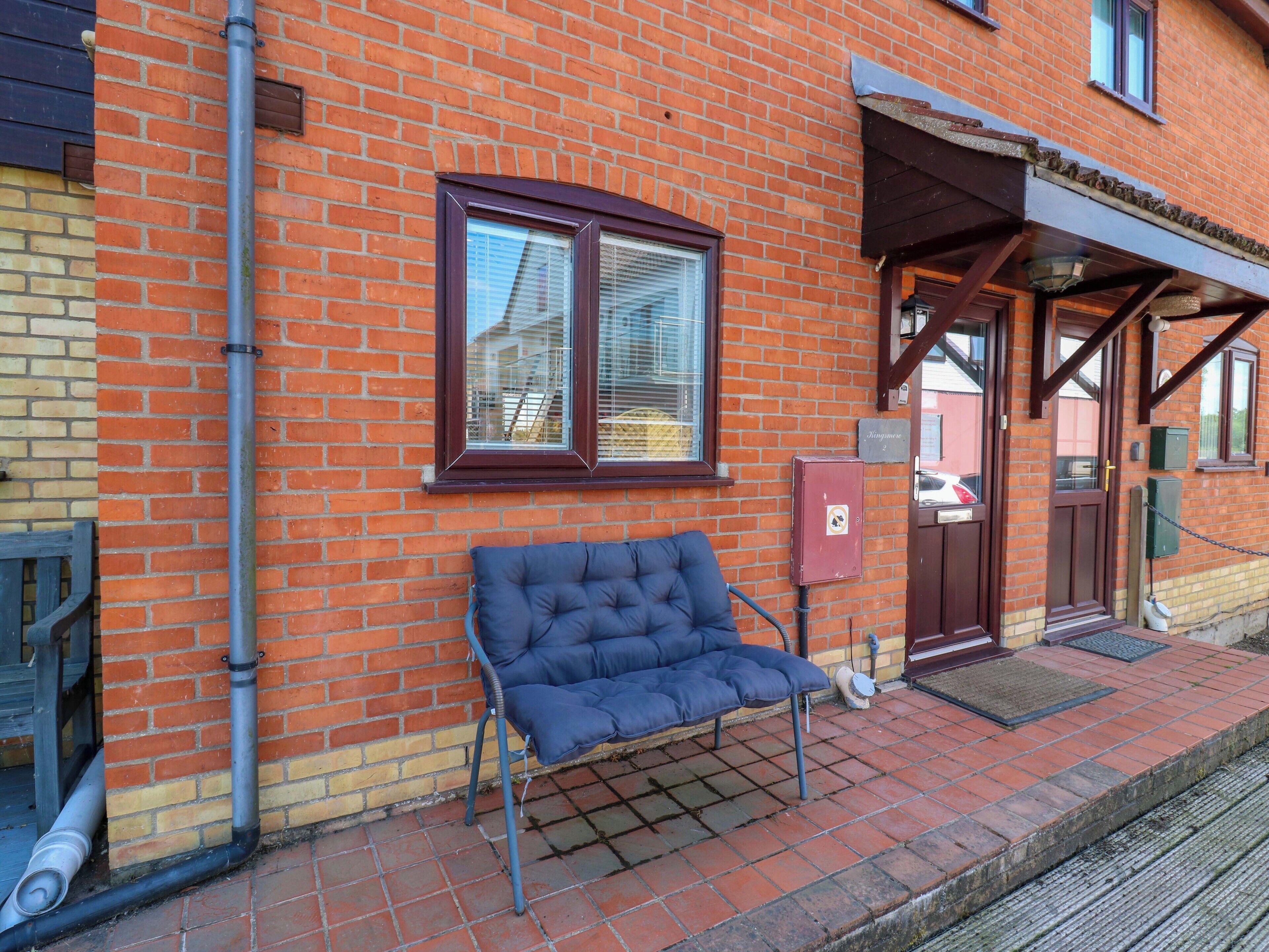A brick building with a bench outside, a door, and a window.