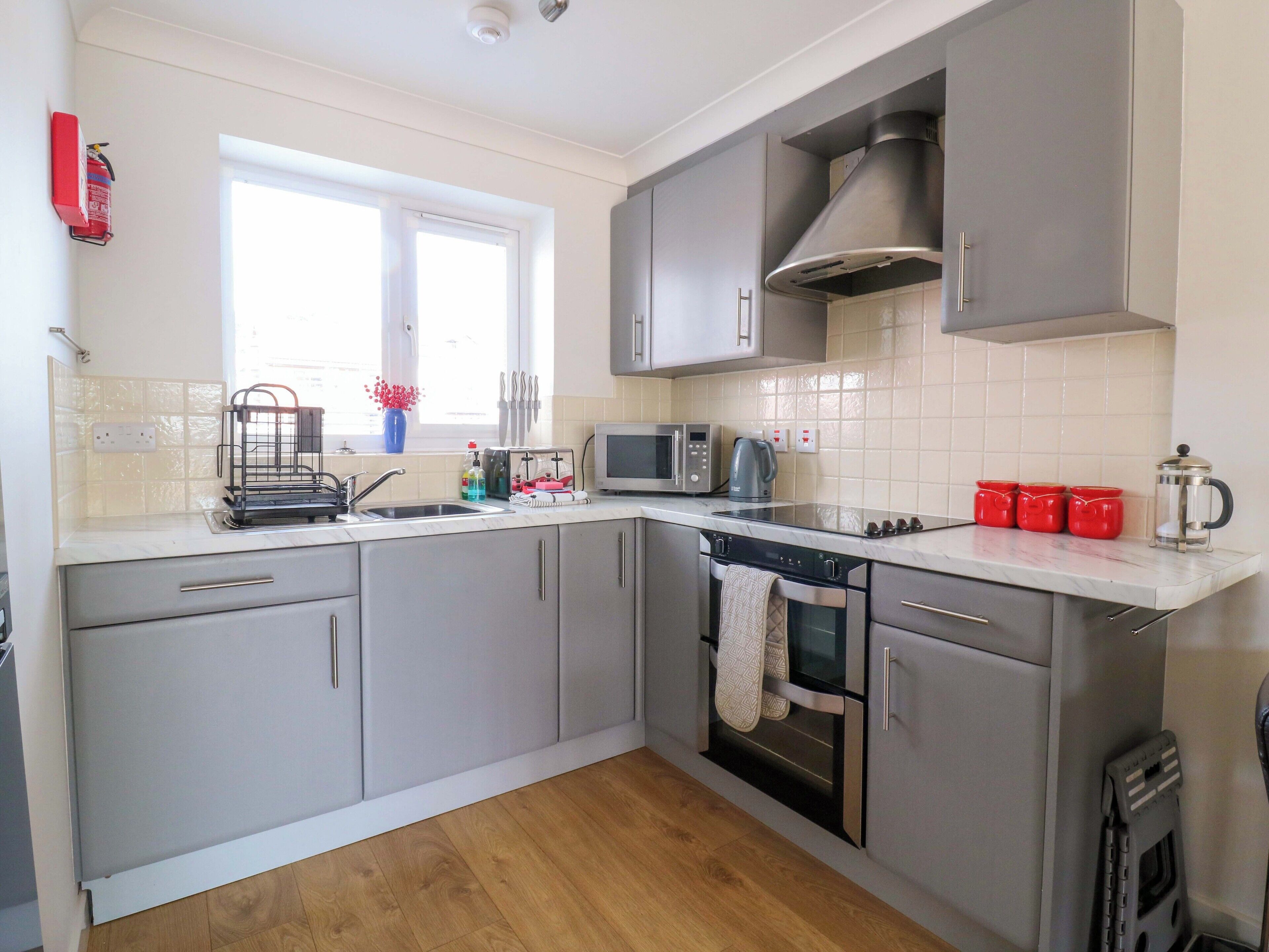 A modern kitchen with grey cabinets, a stainless steel microwave, and a coffee maker.