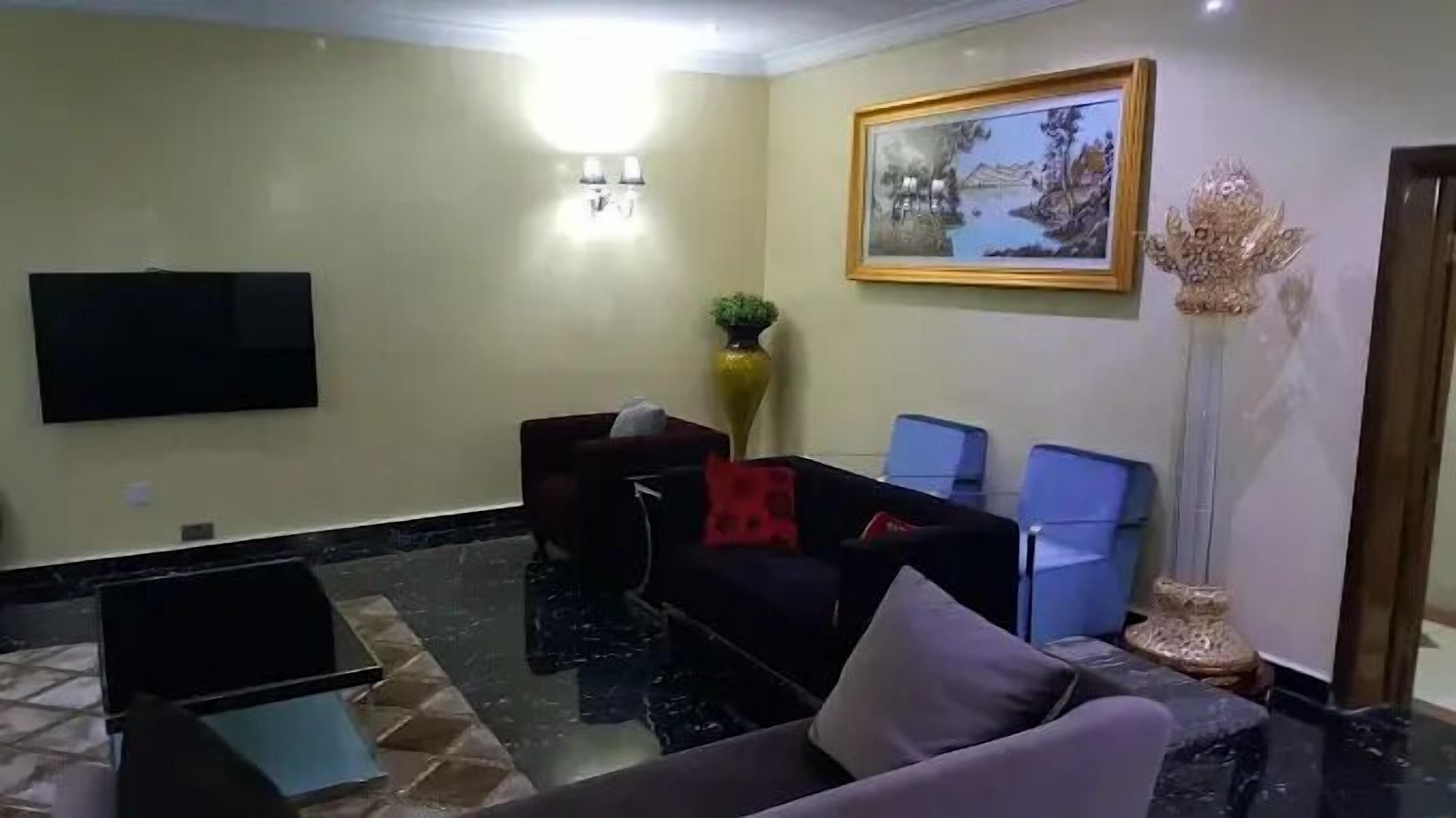 Uma sala de estar com televisão de tela plana, sofá, mesa de centro e um vaso decorativo.