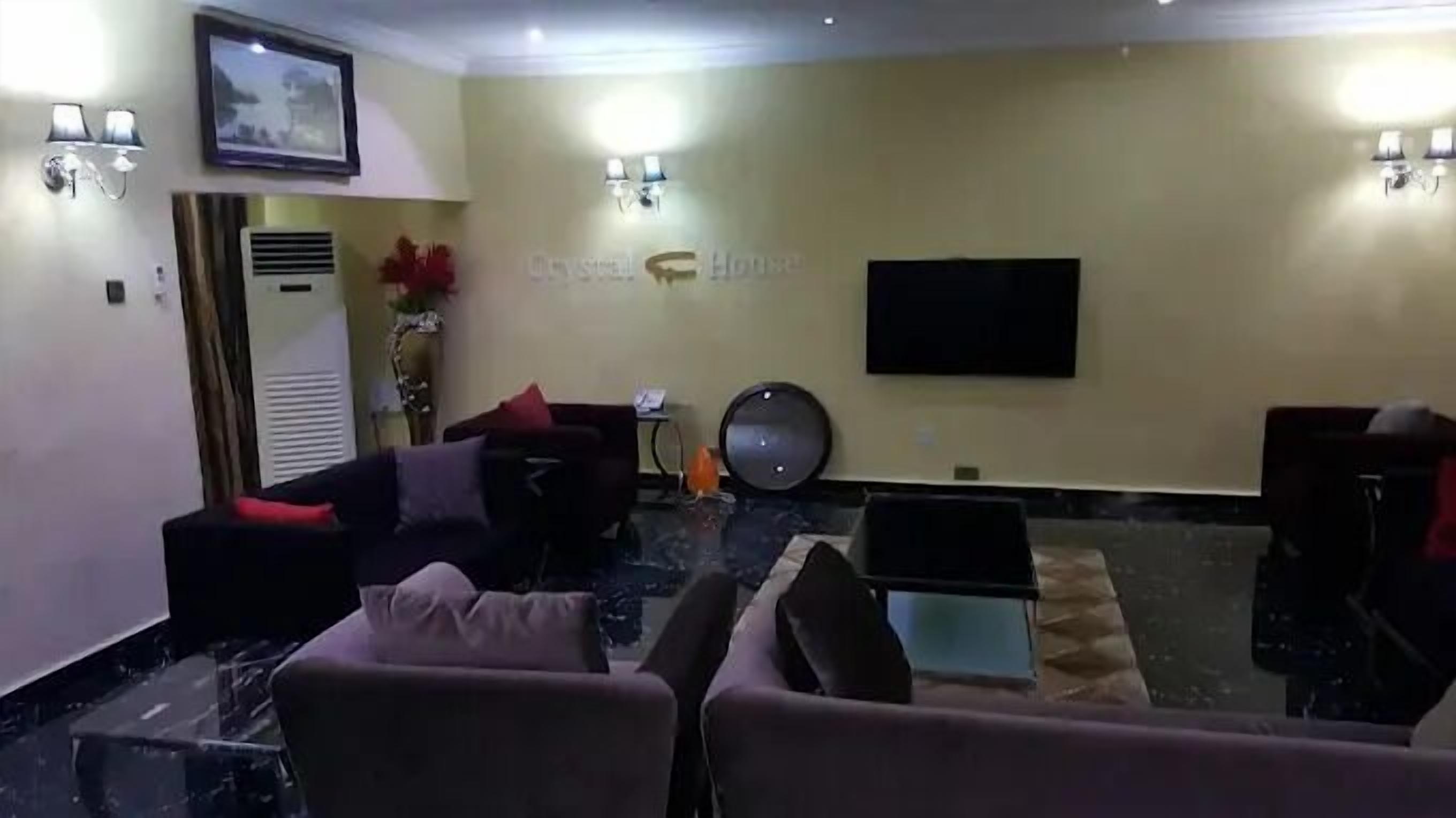 Uma sala de estar moderna com televisão de tela plana, assentos confortáveis e uma parede decorativa com um logotipo.