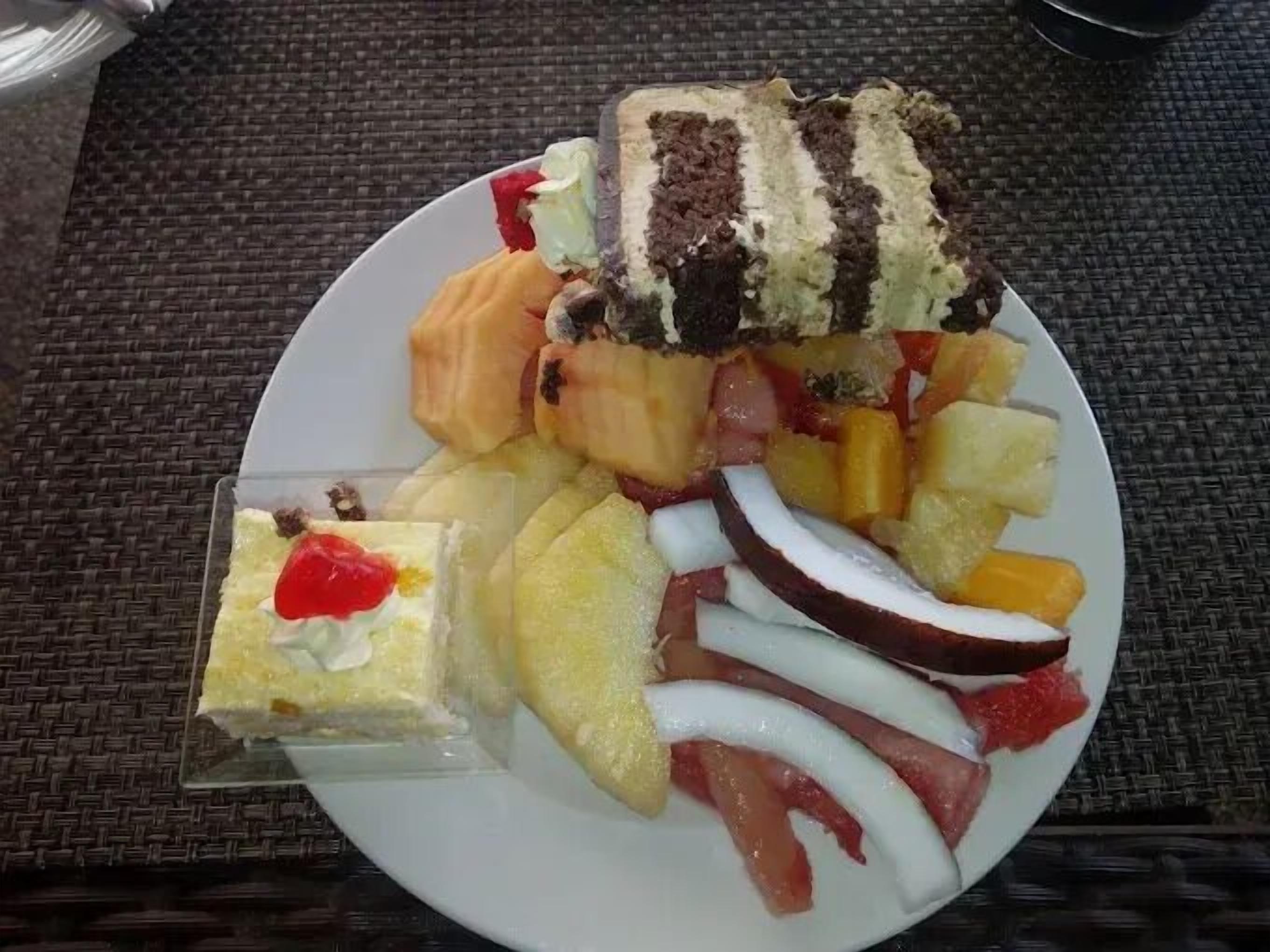 A plate with a variety of fruits and a slice of cake.