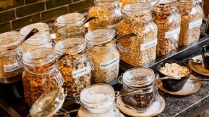 A variety of food items in glass jars with labels, including honey corn and almonds, displayed on a counter. - Gausta Sportell (Tinn)