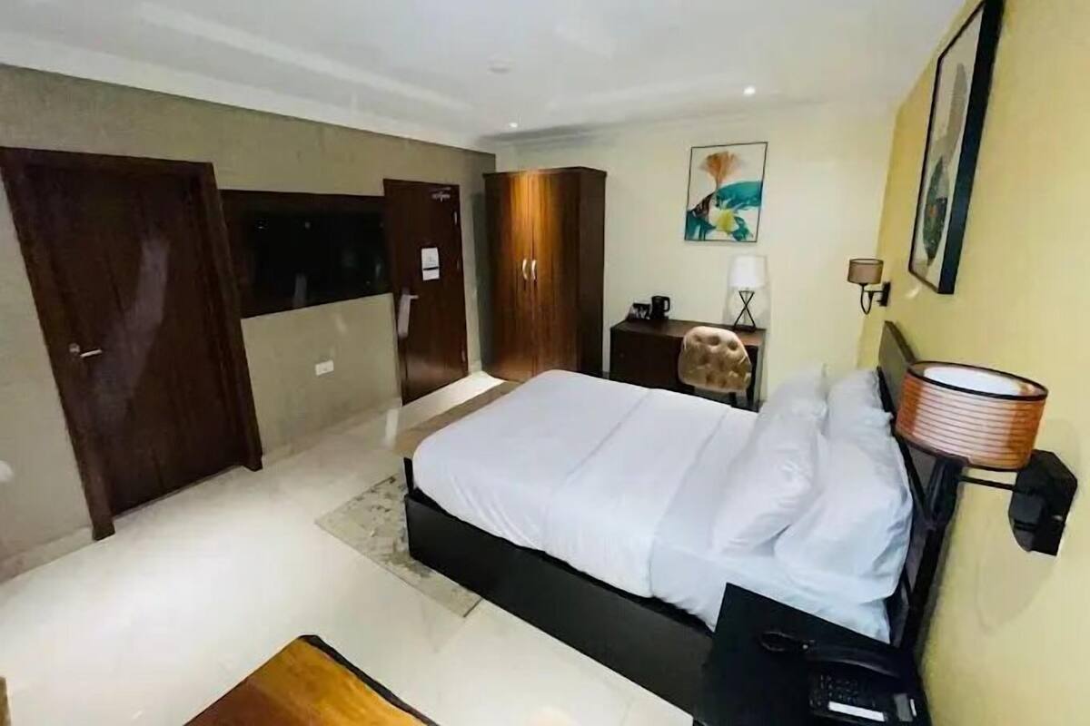 Ein modernes Hotelzimmer mit einem großen Bett, einem Schreibtisch, einem Stuhl und einem Kleiderschrank.