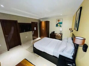 Una habitación de hotel moderna con una cama grande, un escritorio, una silla y un armario.