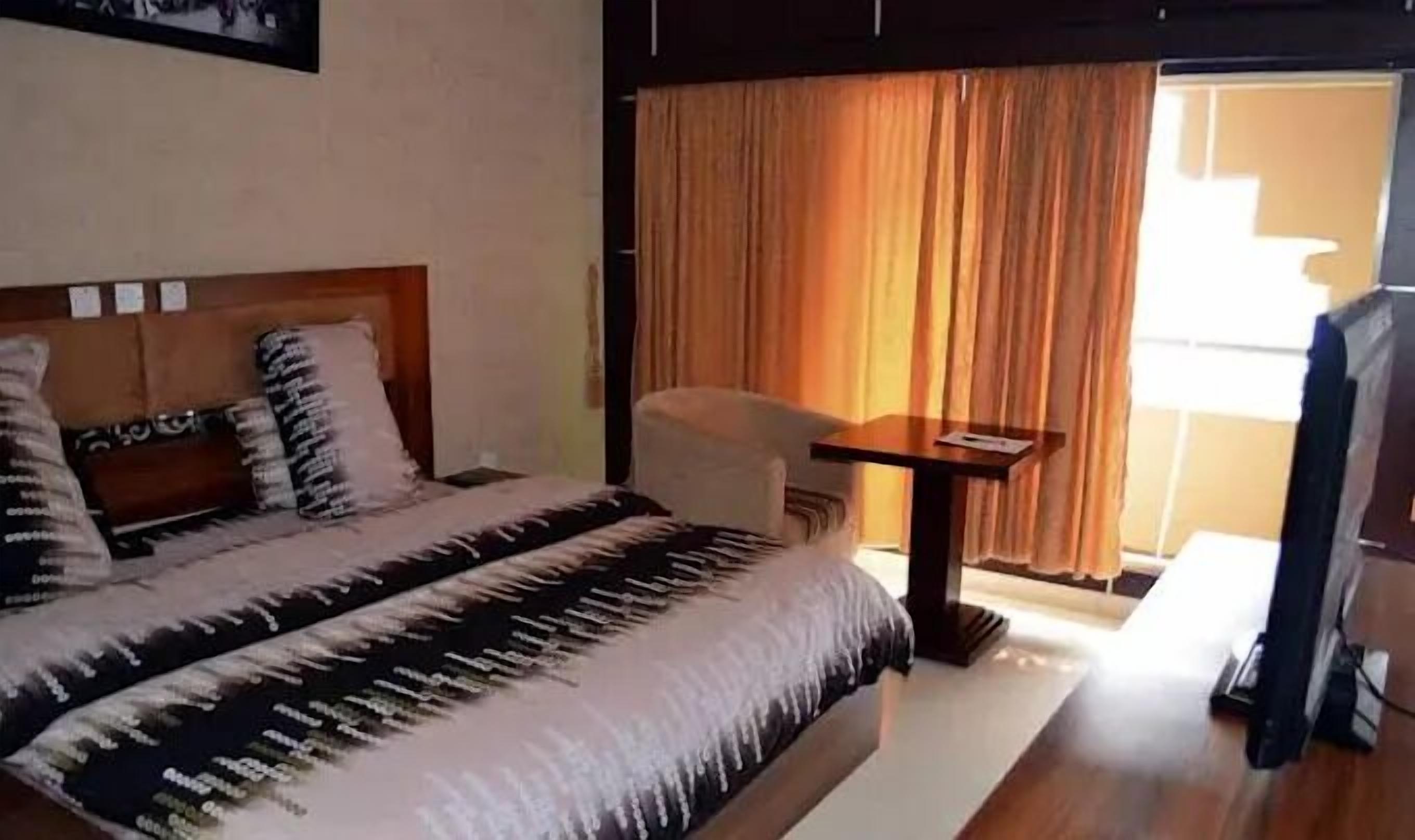 A hotel room with a bed, a small table, and a chair.
