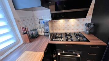 Una cocina compacta con estufa a gas, horno y cafetera.