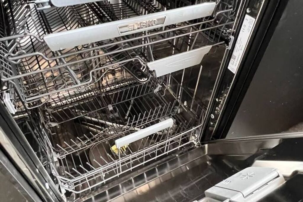 An open dishwasher with multiple racks and a control panel.