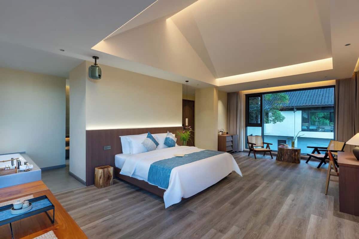 Une chambre d’hôtel moderne dotée d’un grand lit, d’un bureau et offrant une vue sur l’extérieur.