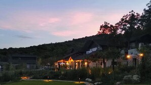 Een goed verlicht resort met een pad naar een gebouw met meerdere ramen en een zichtbaar buitenzitgedeelte.
