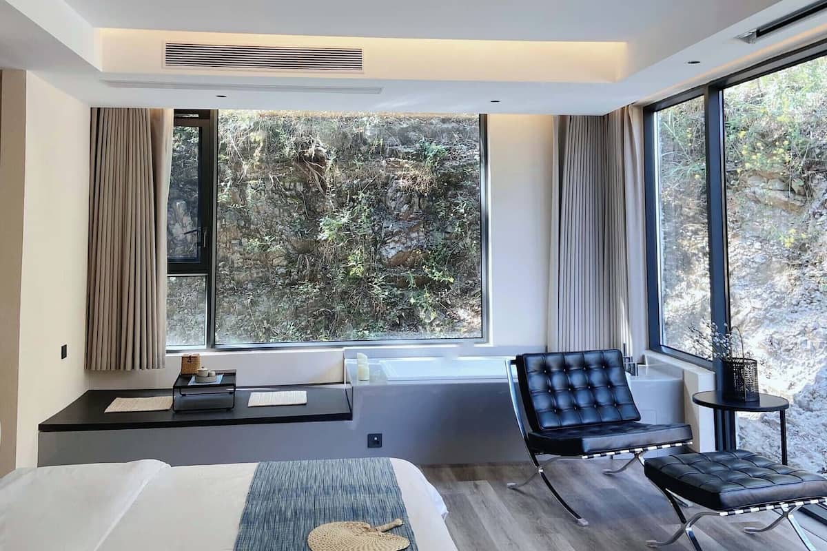 Une chambre moderne dotée d’un grand lit, d’un coin salon et offrant une vue sur l’extérieur.