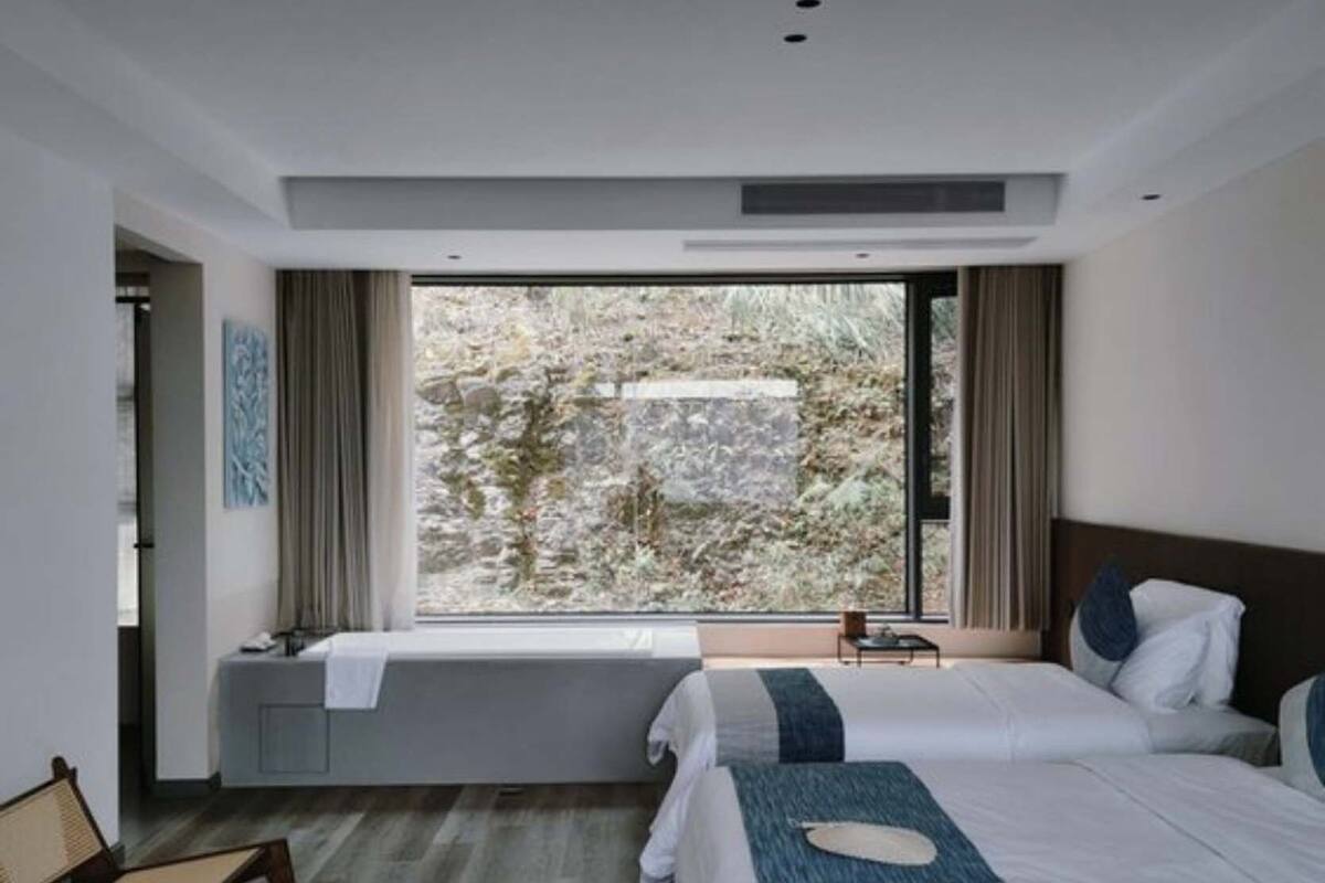 Une chambre moderne avec deux lits, un banc et une vue sur un paysage rocheux.