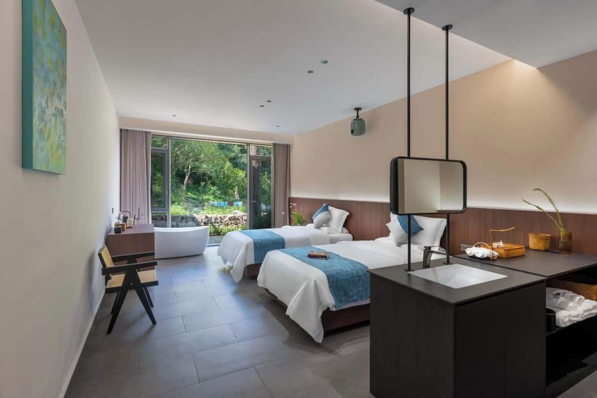 Une chambre d’hôtel moderne équipée de deux lits, d’un bureau et d’une salle de bain.