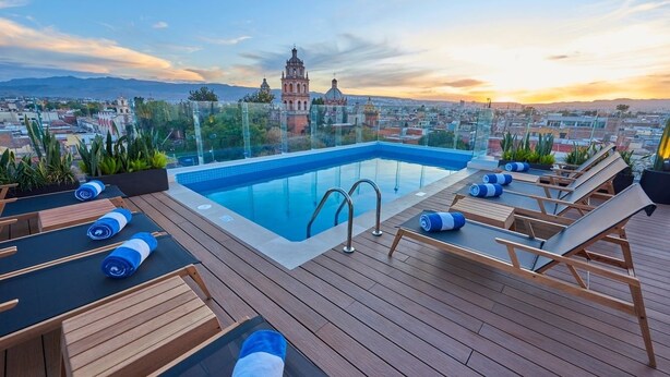 A rooftop pool with lounge chairs and a clear view of a historic building in the background. - Trendy & Comfy Room in Historic Center | Explore San Luis Like a Local (San Luis Potosí)