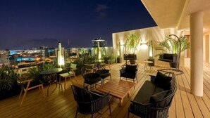 A rooftop terrace with outdoor seating, potted plants, and a city view at night. - Trendy & Comfy Room in Historic Center | Explore San Luis Like a Local (San Luis Potosí)