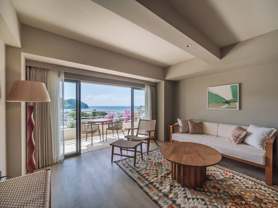 Une pièce spacieuse avec un balcon, un canapé, une table basse et une vue sur la mer.
