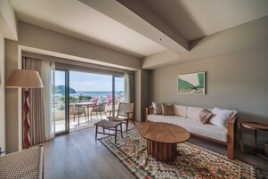 Una habitación amplia con balcón, sofá, mesa de centro y vistas al mar.