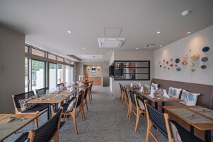 A restaurant with multiple dining tables, chairs, and a kitchen area in the background.