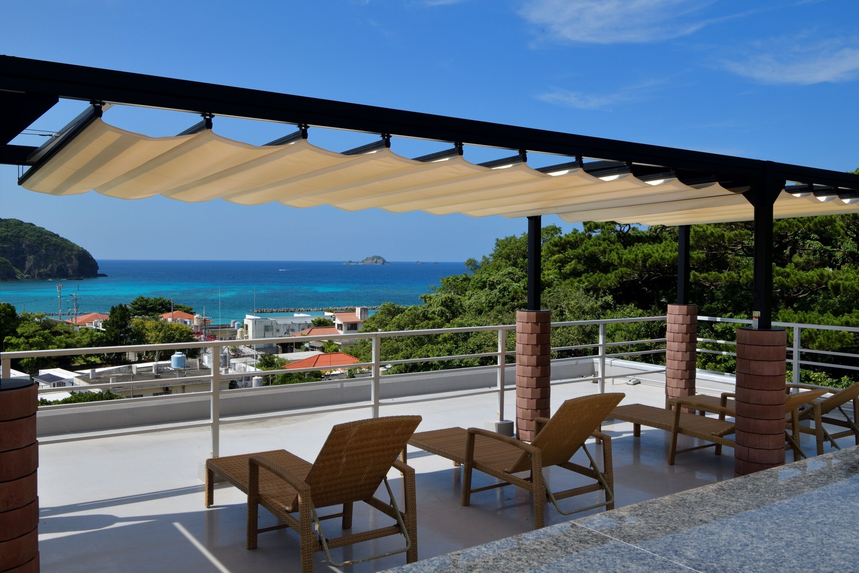 Un balcone con mobili da esterno, vista sul mare e cielo sereno.