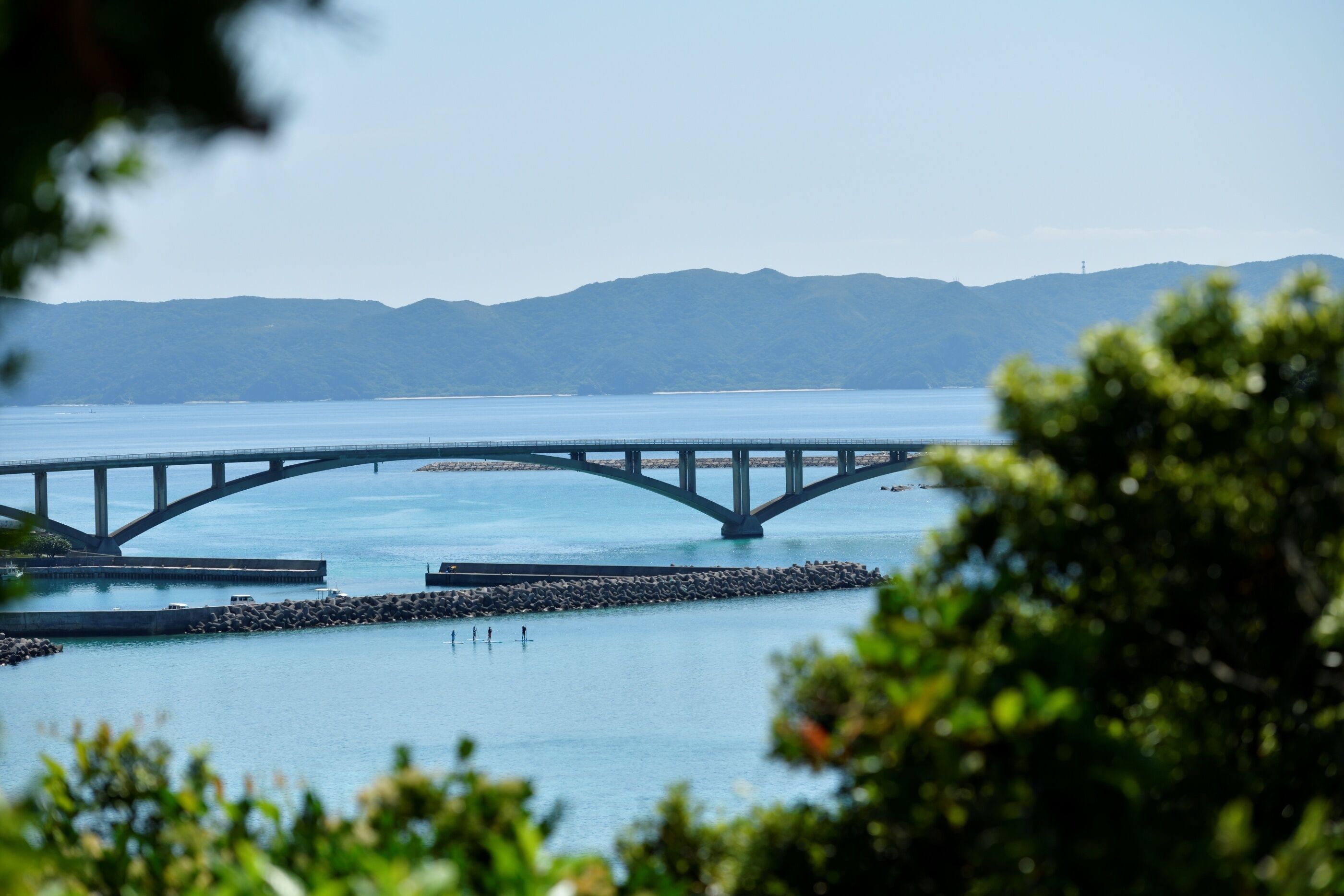 A bridge over water with mountains in the background.