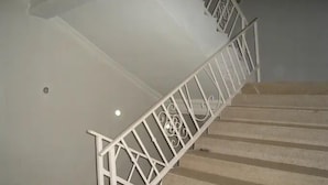 Una escalera con barandillas blancas y escalones color beige.