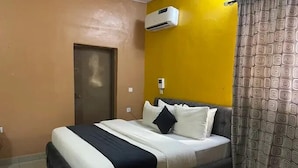 Un dormitorio con cama, aire acondicionado, una puerta y cortina estampada.