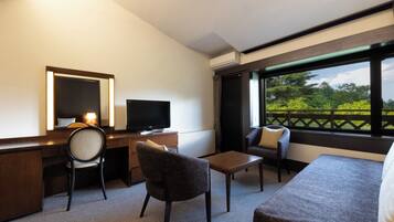 Een hotelkamer met een bureau, stoel, televisie en een bank.