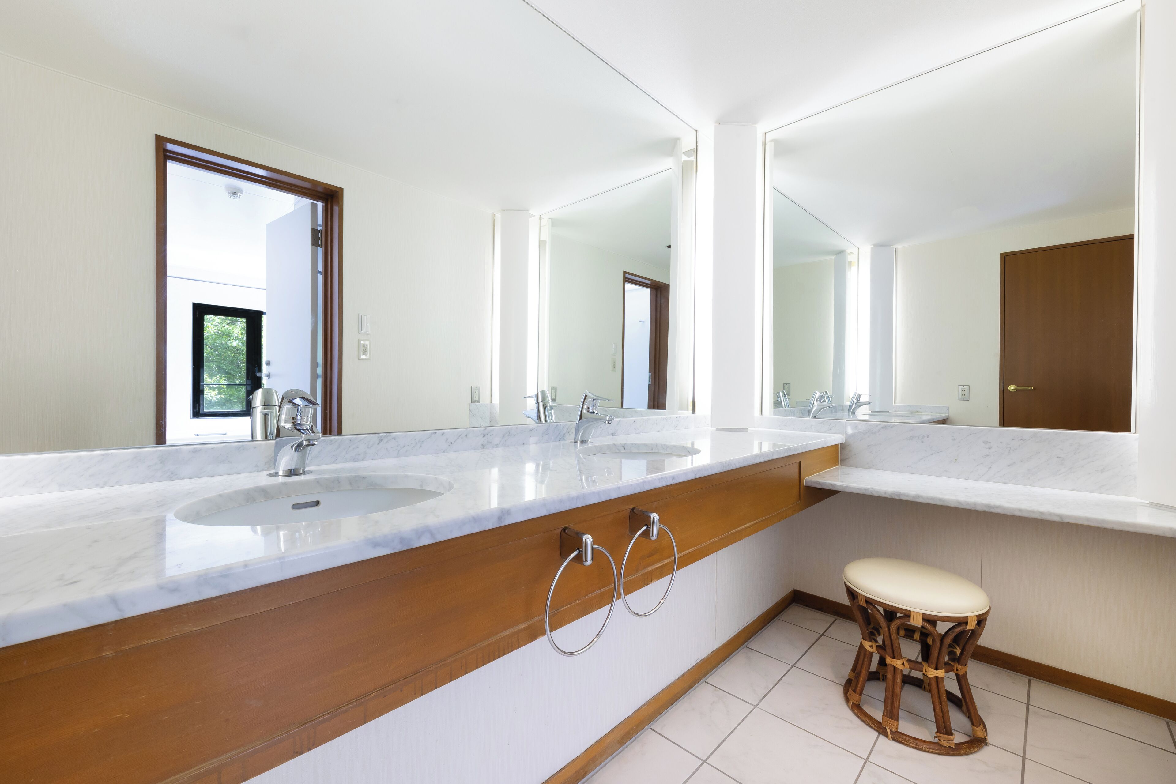 A modern bathroom with two sinks, large mirrors, and a wooden vanity.
