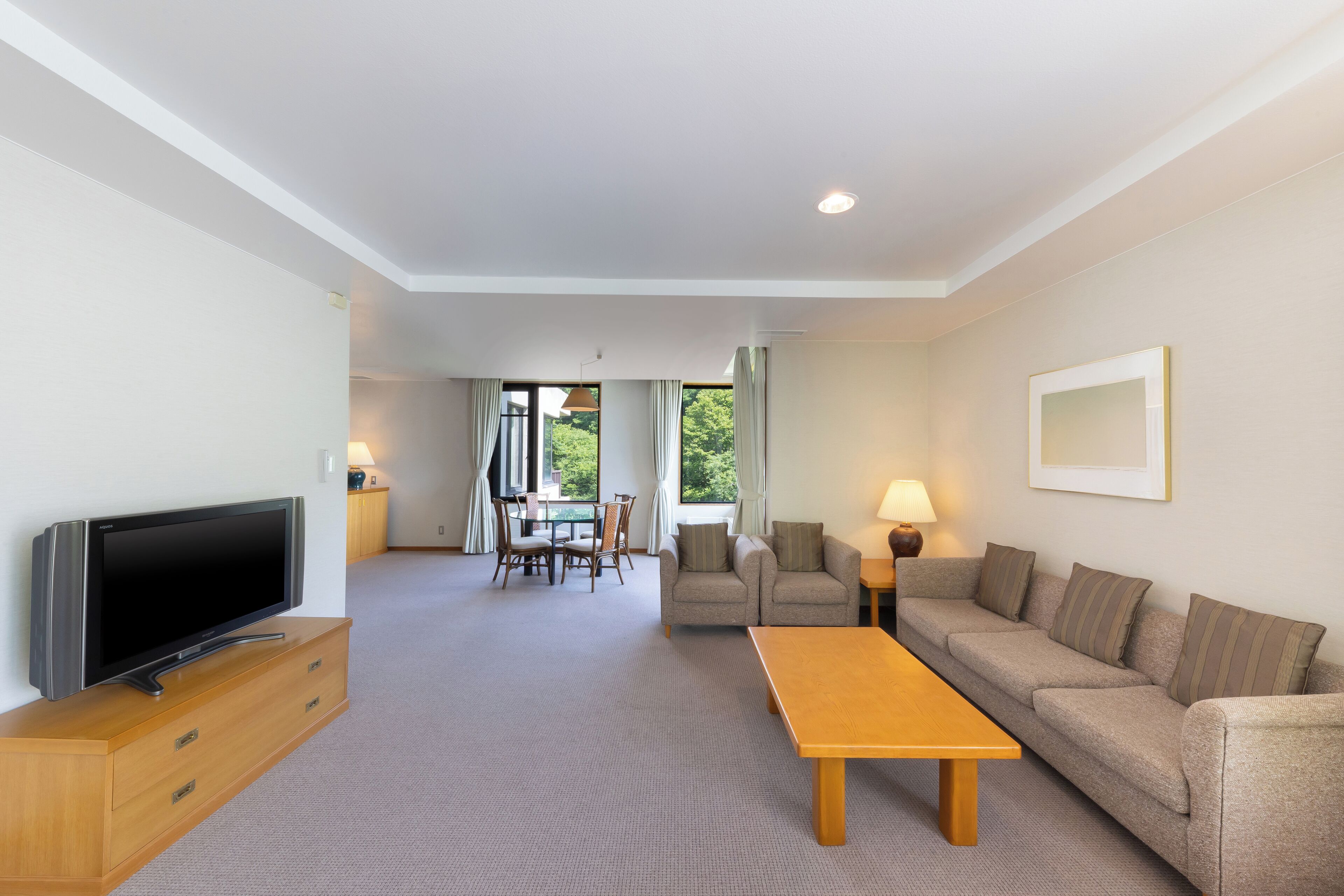 A modern living room with a flat-screen TV, wooden cabinet, sofa, and a table.