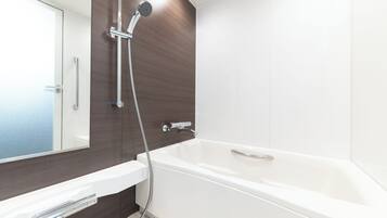 A modern bathroom with a white bathtub, a handheld showerhead, and a glass-enclosed shower area.