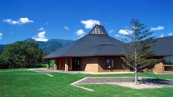 A modern building with a sloped roof, surrounded by a well-maintained lawn and a small tree.