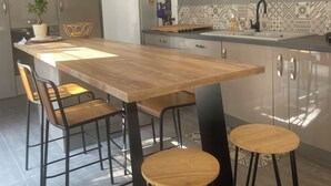 A modern kitchen with a wooden island, bar stools, and stainless steel appliances. - Charming villa in Provence (Piolenc)