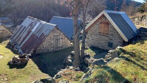Une rangée de maisons en pierre aux toits inclinés, entourées d’un paysage rocheux et avec une montagne en arrière-plan.