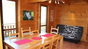 A wooden cabin with a dining table, chairs, and a sofa. - Les Castors - ROUBION (ROUBION)