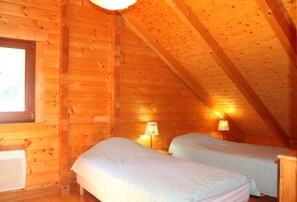 A cozy attic bedroom with two single beds, wooden walls, and a sloped ceiling. - Les Castors - ROUBION (ROUBION)