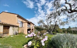A rustic building with a balcony, surrounded by a well-maintained garden with flowering plants and a large tree. - Villa les Seringas - MOUGINS (MOUGINS)