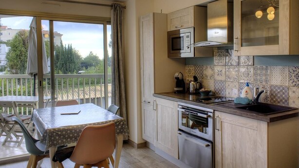 A kitchen with a dining area, a balcony with a table and chairs, and a view of the outside.
