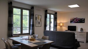 Ein modernes Wohnzimmer mit Esstisch, Sofa und Fernseher.